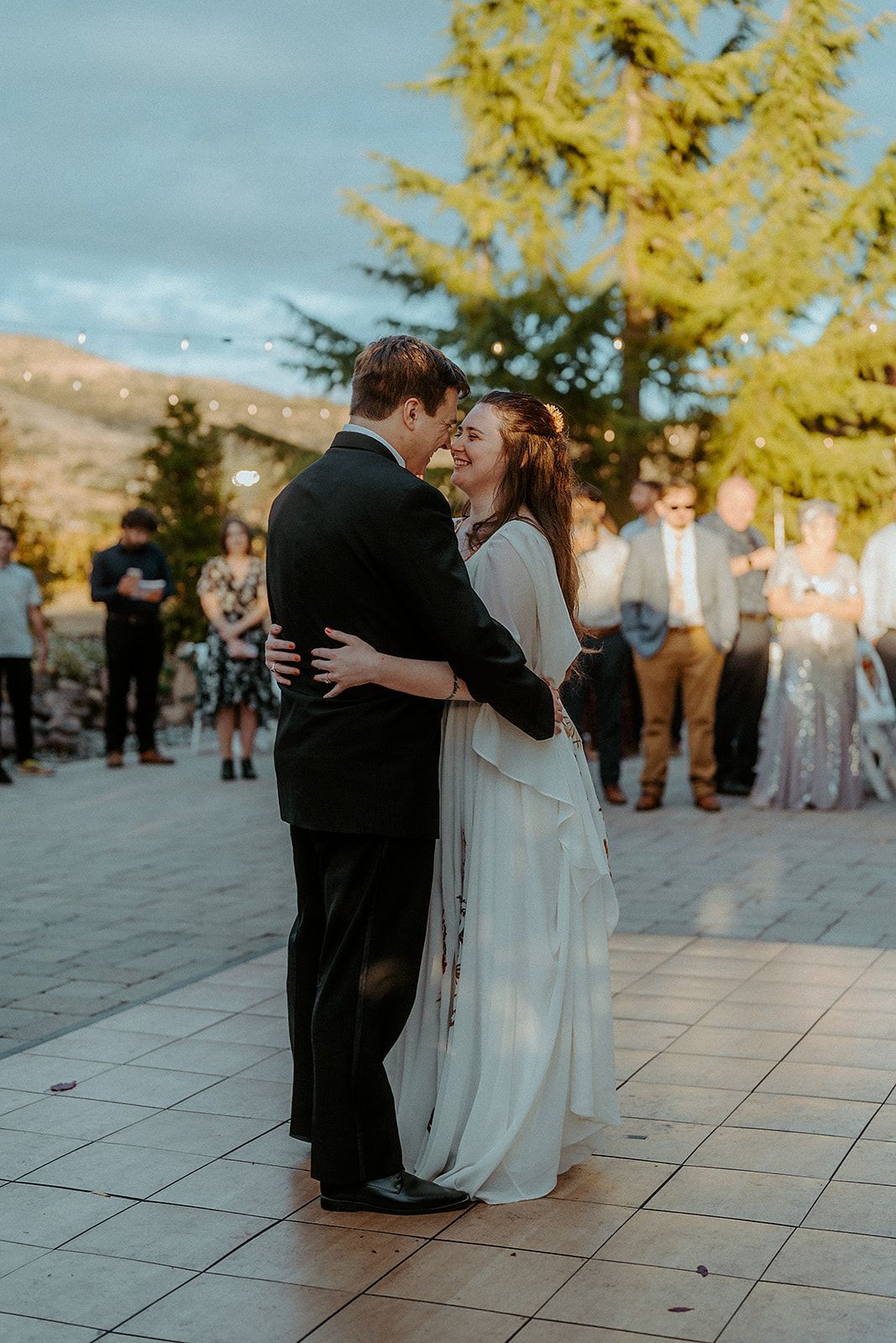 A bride and groom are kissing during their first dance at their wedding reception.