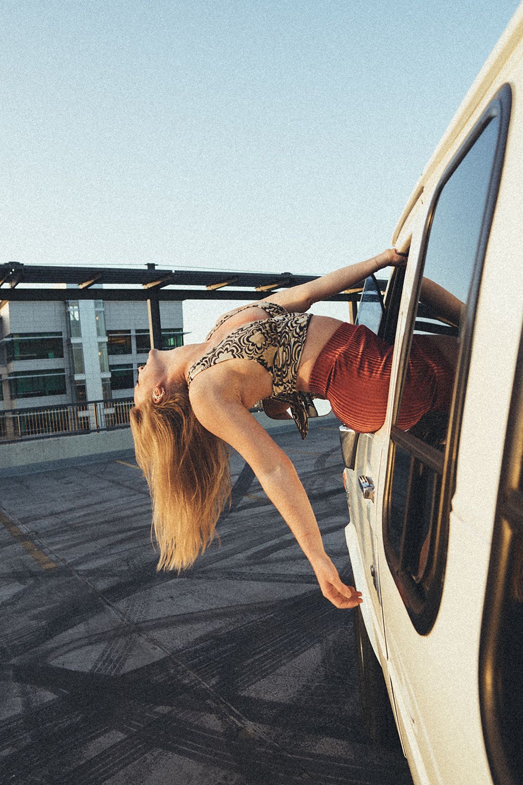 A woman is doing a handstand in front of a van.
