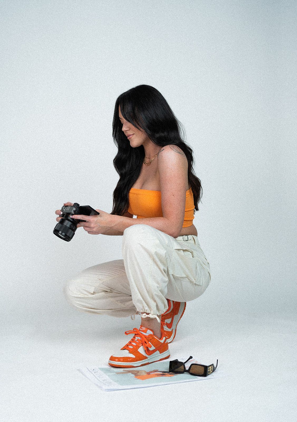 A woman is squatting down while holding a camera.