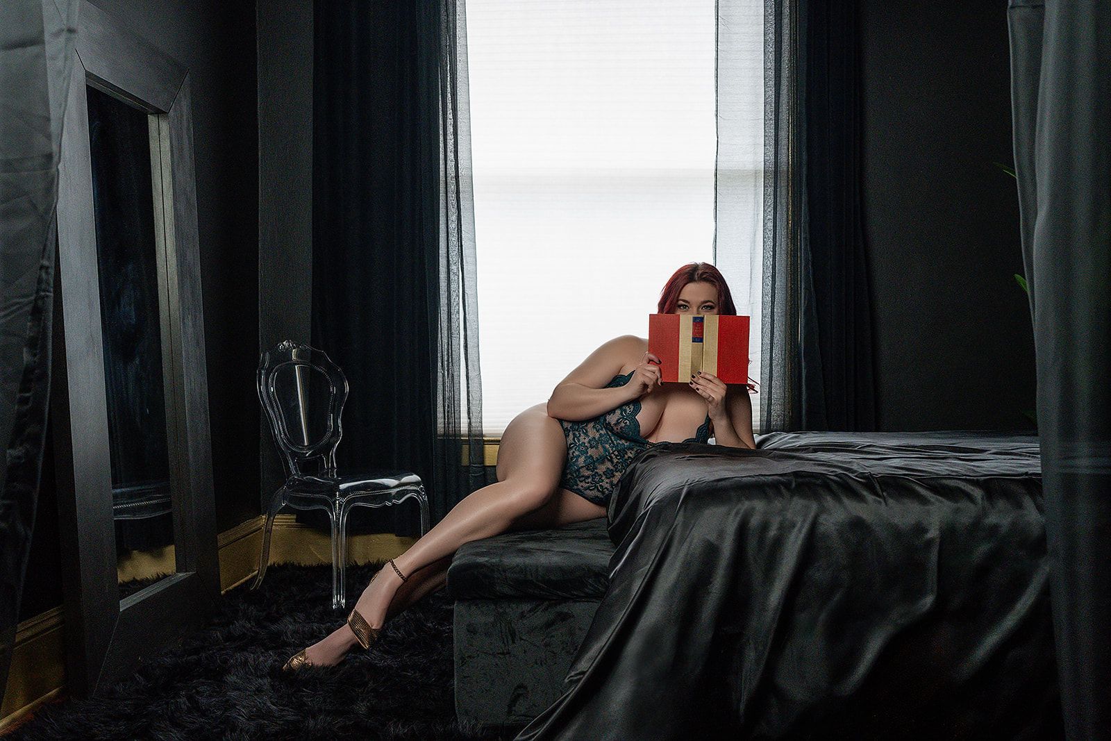 A woman in lingerie is laying on a bed in the dark.