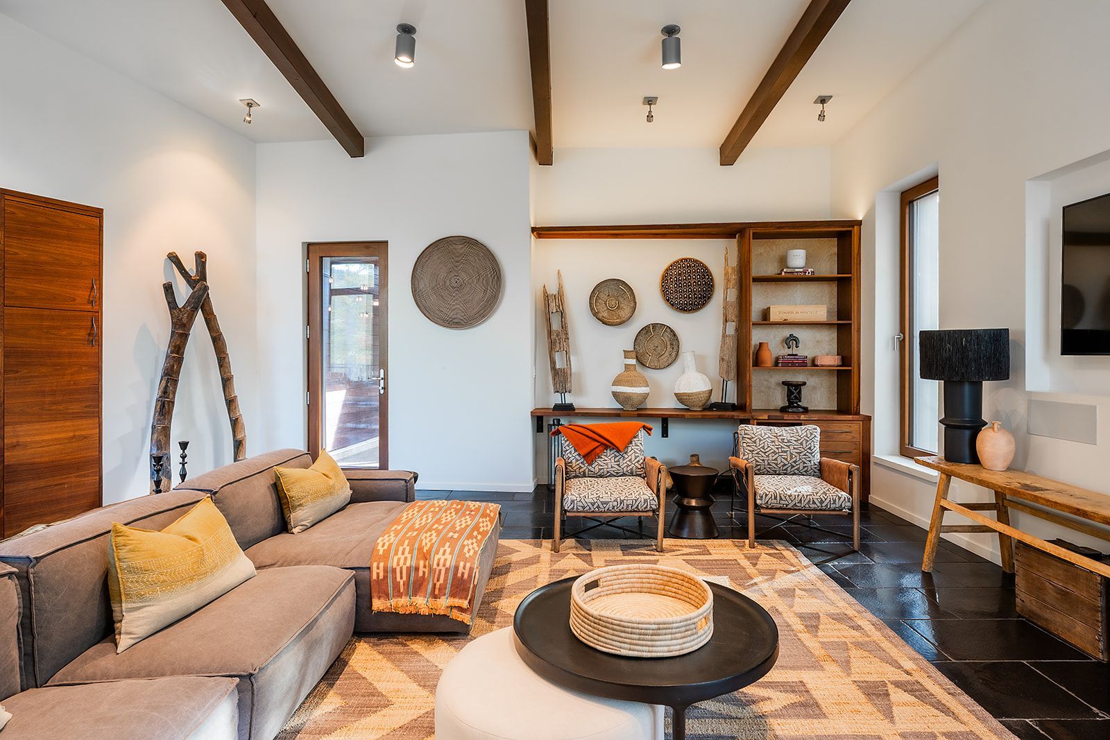 A living room with a couch , chairs , ottoman , table and television.