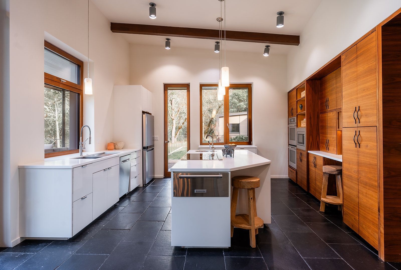A kitchen with white cabinets and wooden cabinets and a large island in the middle.