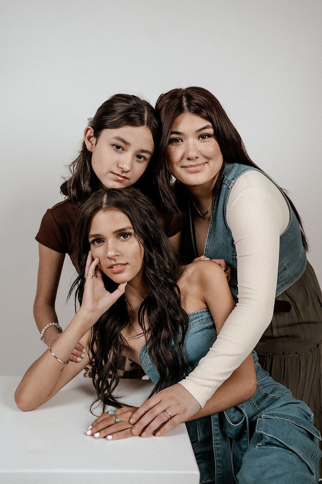 Three women are posing for a picture together while sitting at a table.
