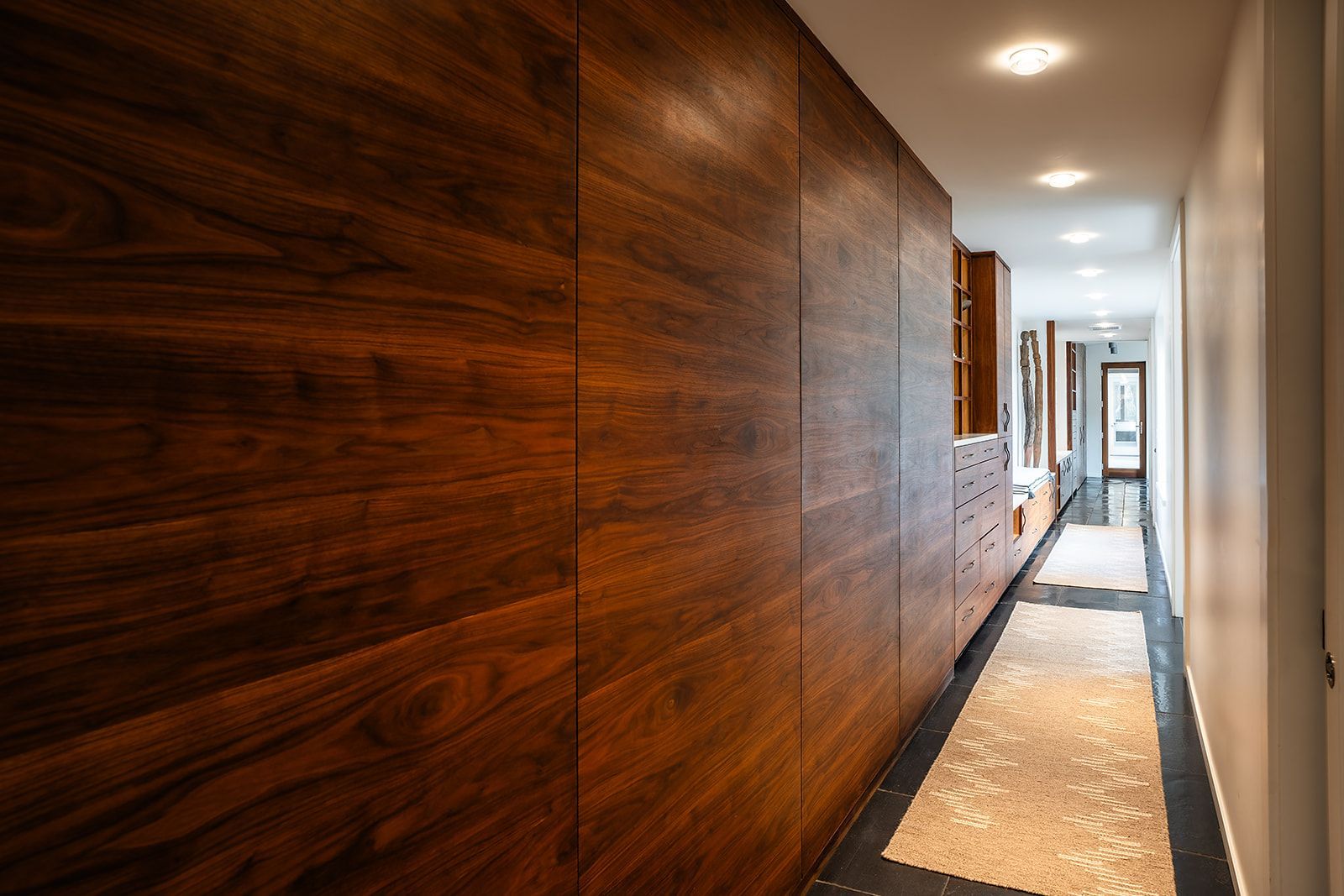 A long hallway with wooden walls and a rug.