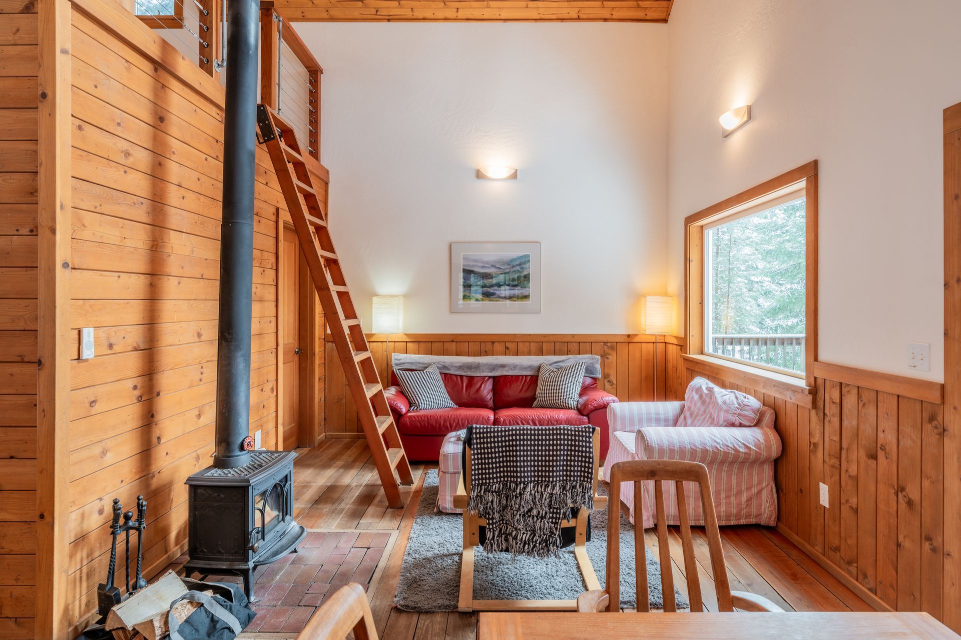 A living room with a couch , chairs , a table and a wood stove.