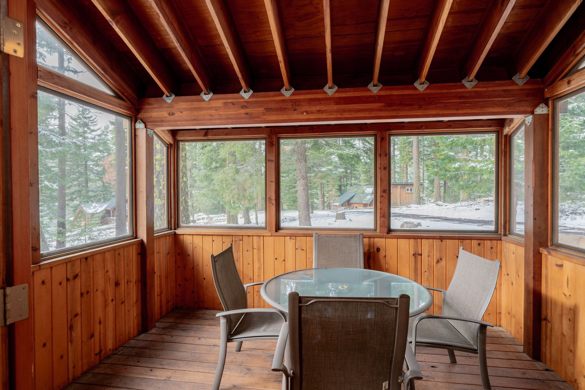 A screened in porch with a table and chairs.