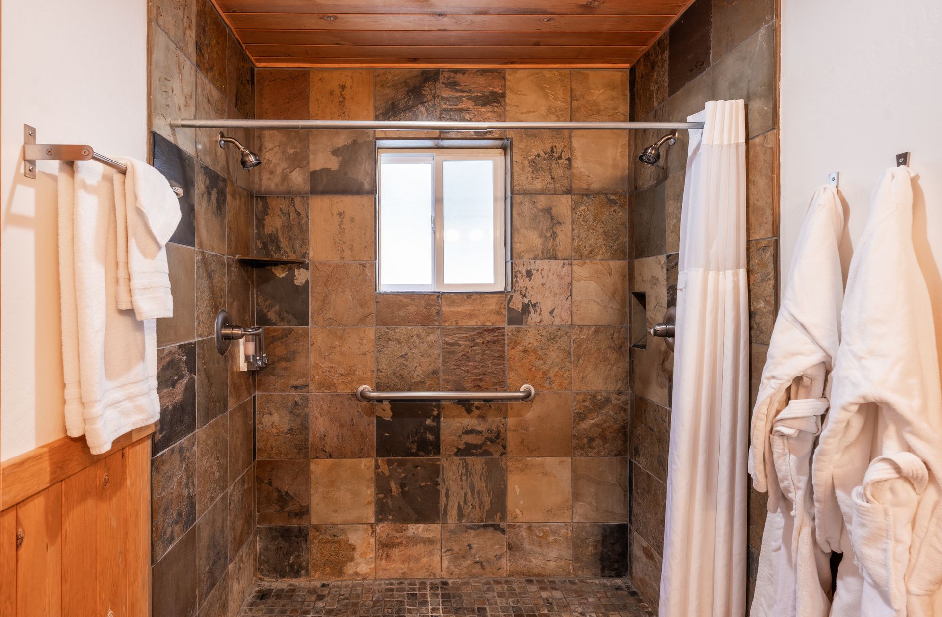 A bathroom with a walk in shower and a window.