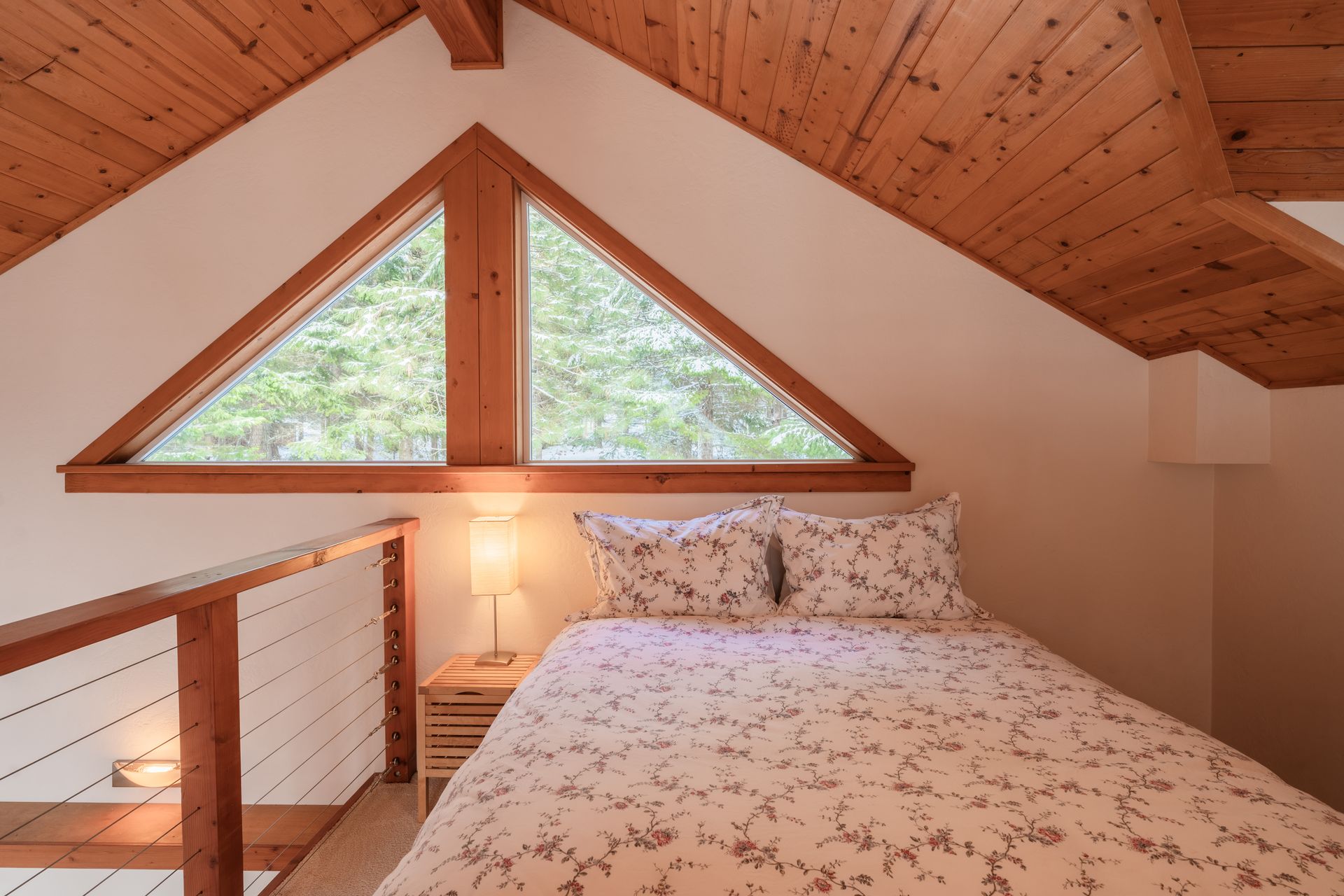 A bedroom with a triangle shaped window and a bed