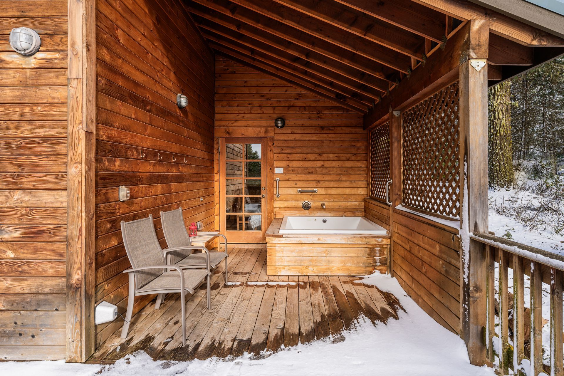There is a hot tub on the porch of a wooden cabin.