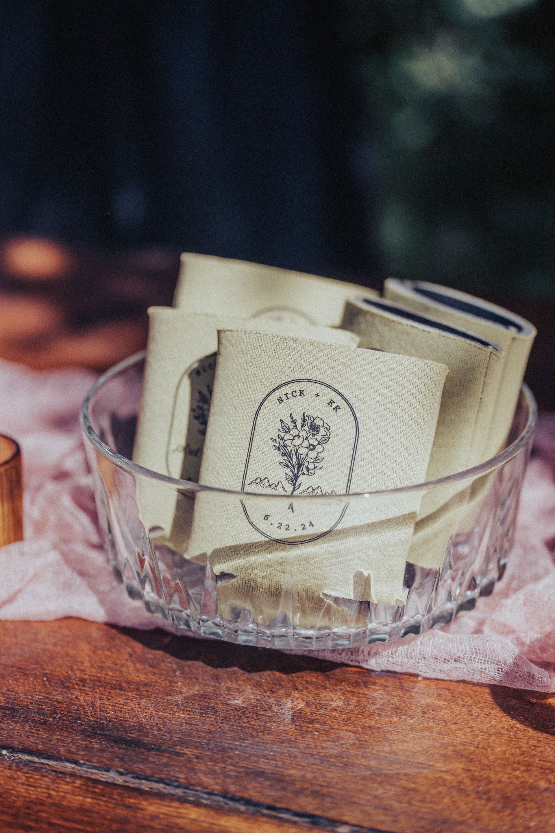 A glass bowl filled with envelopes on a wooden table.
