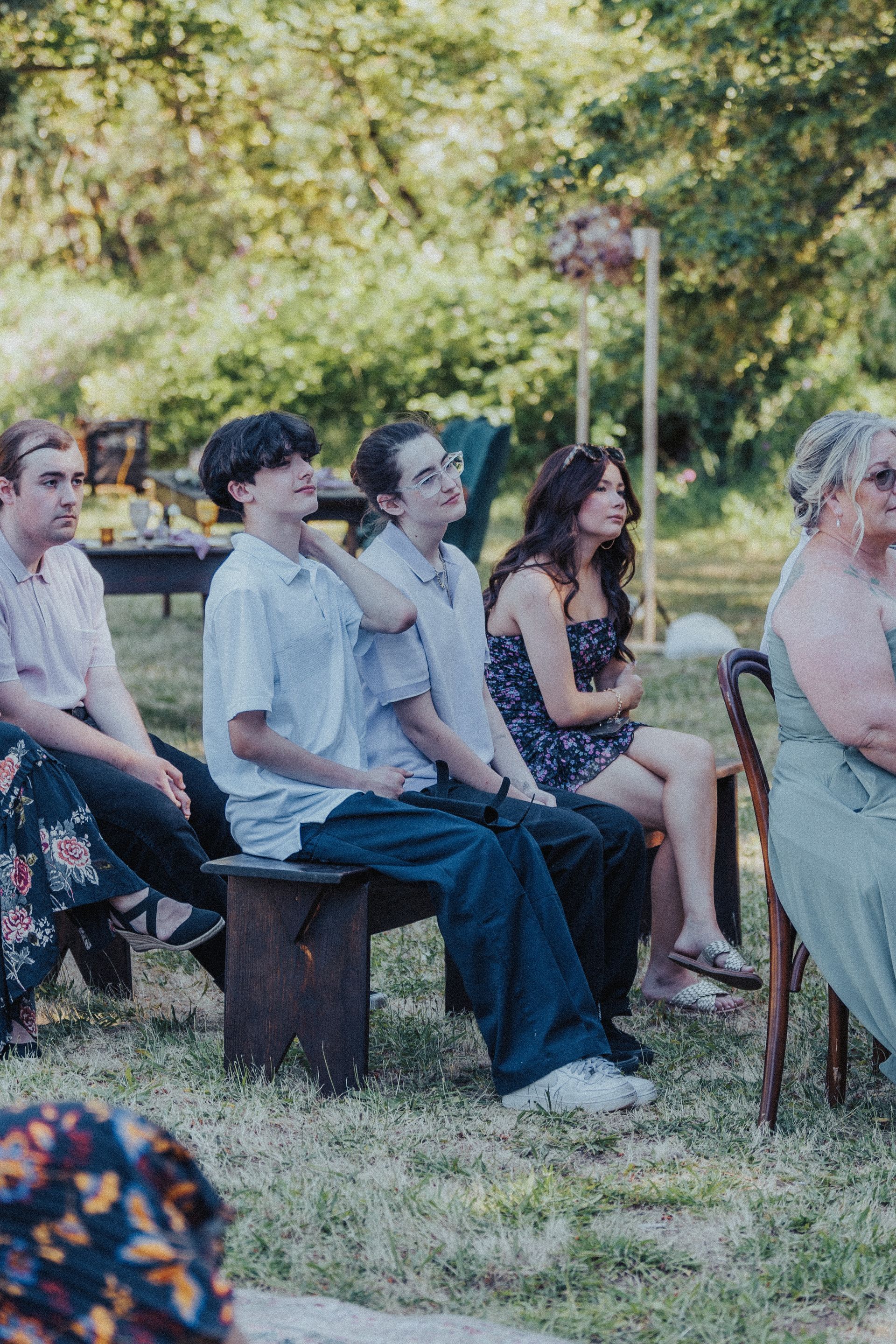 A group of people are sitting on benches in the grass.