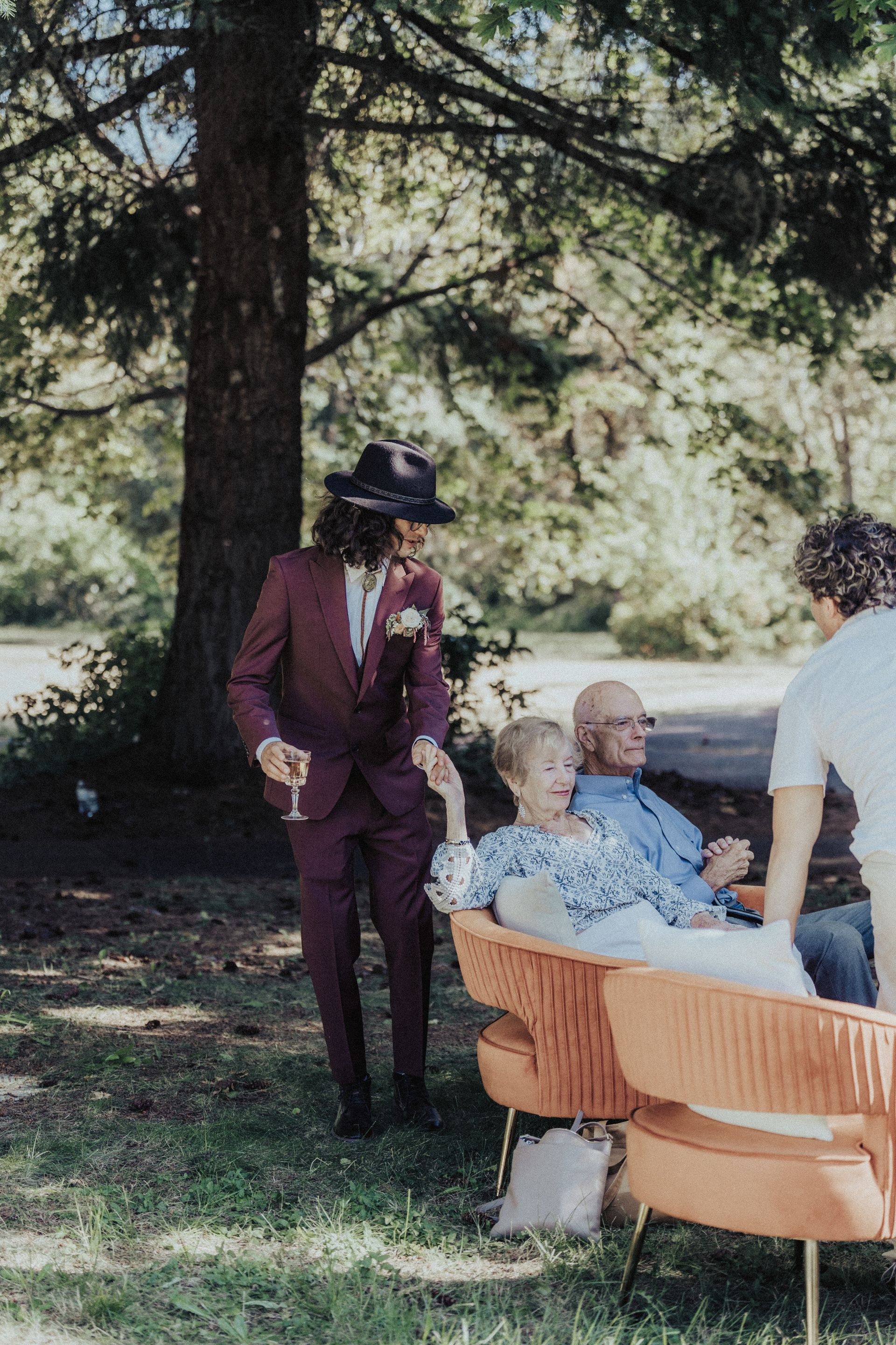 A man in a suit is standing next to a woman sitting on a chair.