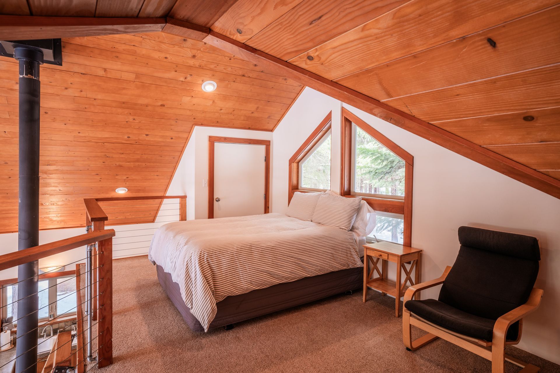 A bedroom with a bed and a chair in the attic.