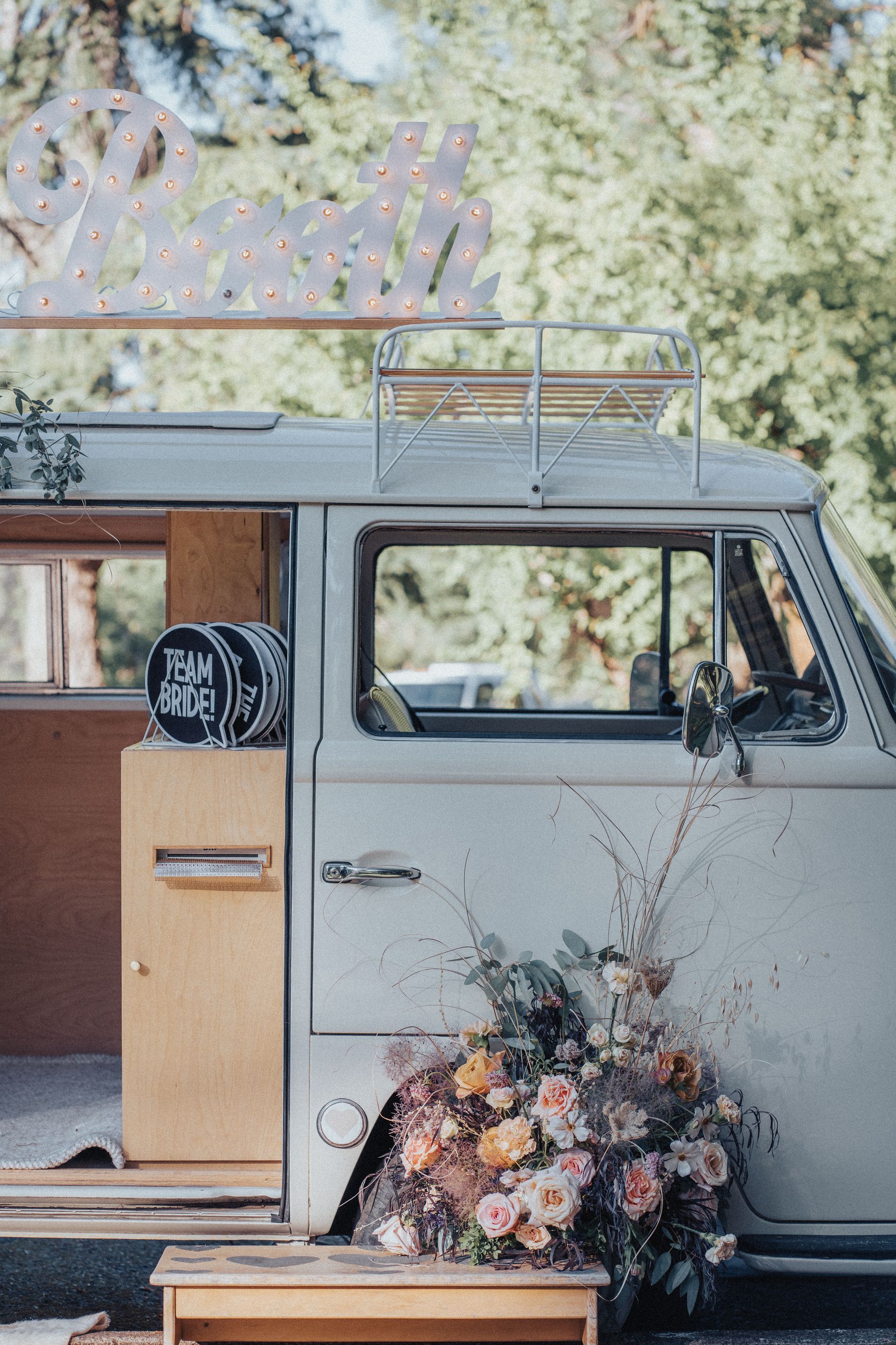A camper van with flowers in the back is parked on the side of the road.