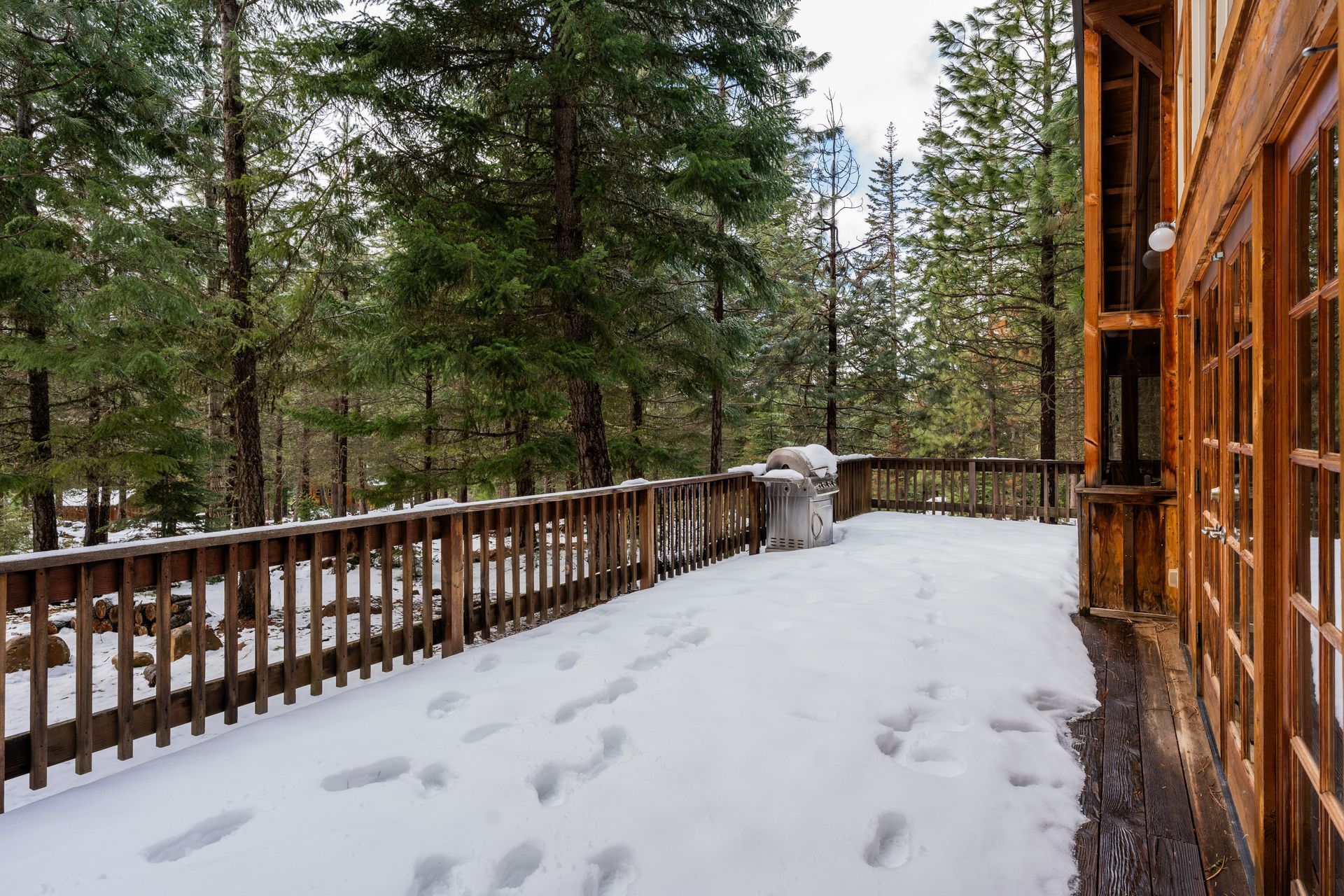 A wooden deck covered in snow with trees in the background.