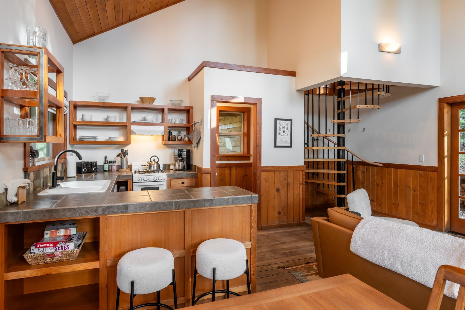A kitchen and dining room in a house with a spiral staircase leading to the second floor.