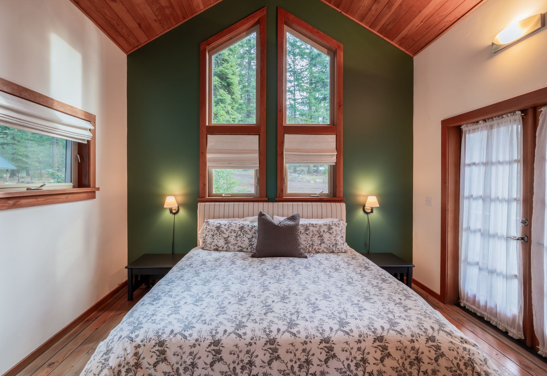 A bedroom with a bed , two windows and a vaulted ceiling.
