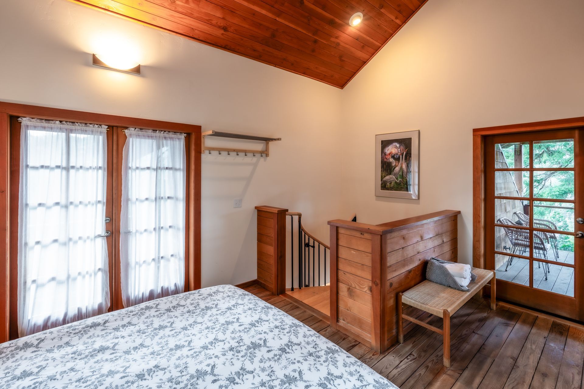 A bedroom with a bed , stairs , and a bench.