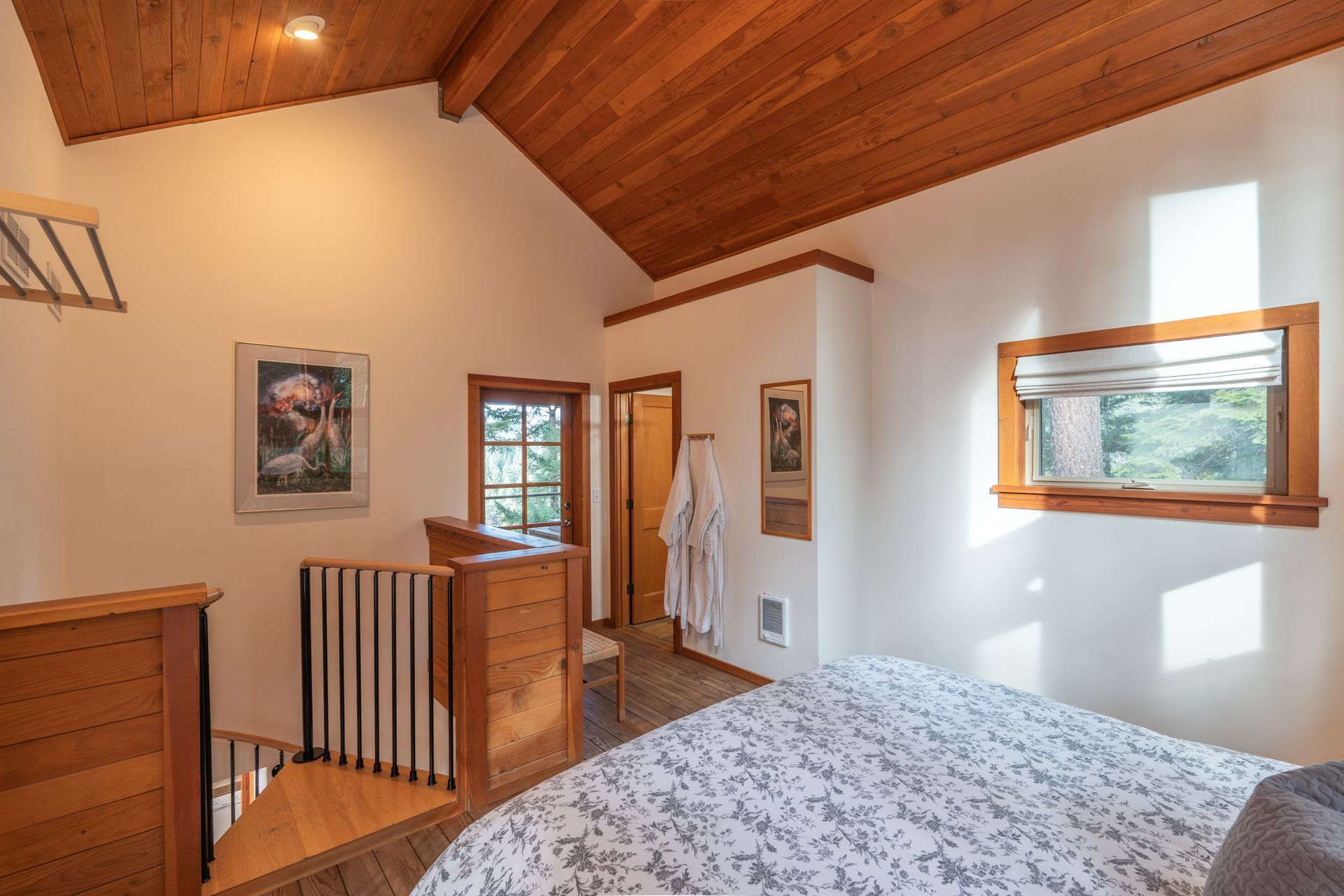 A bedroom with a king size bed and a spiral staircase leading to the second floor.