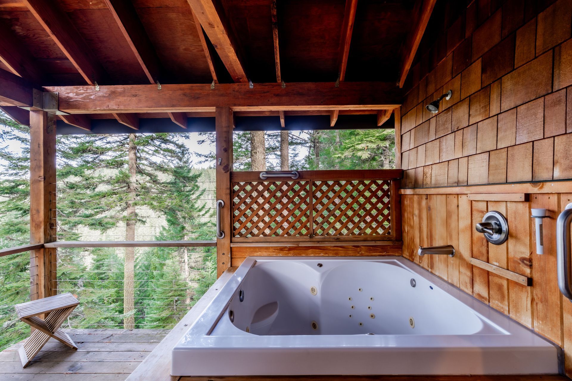 A jacuzzi tub on a porch with a view of the woods