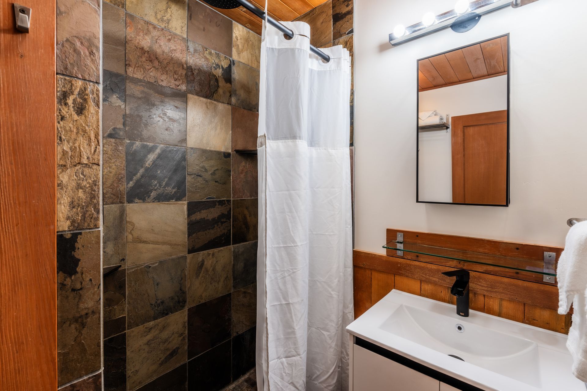 A bathroom with a sink , mirror and shower.