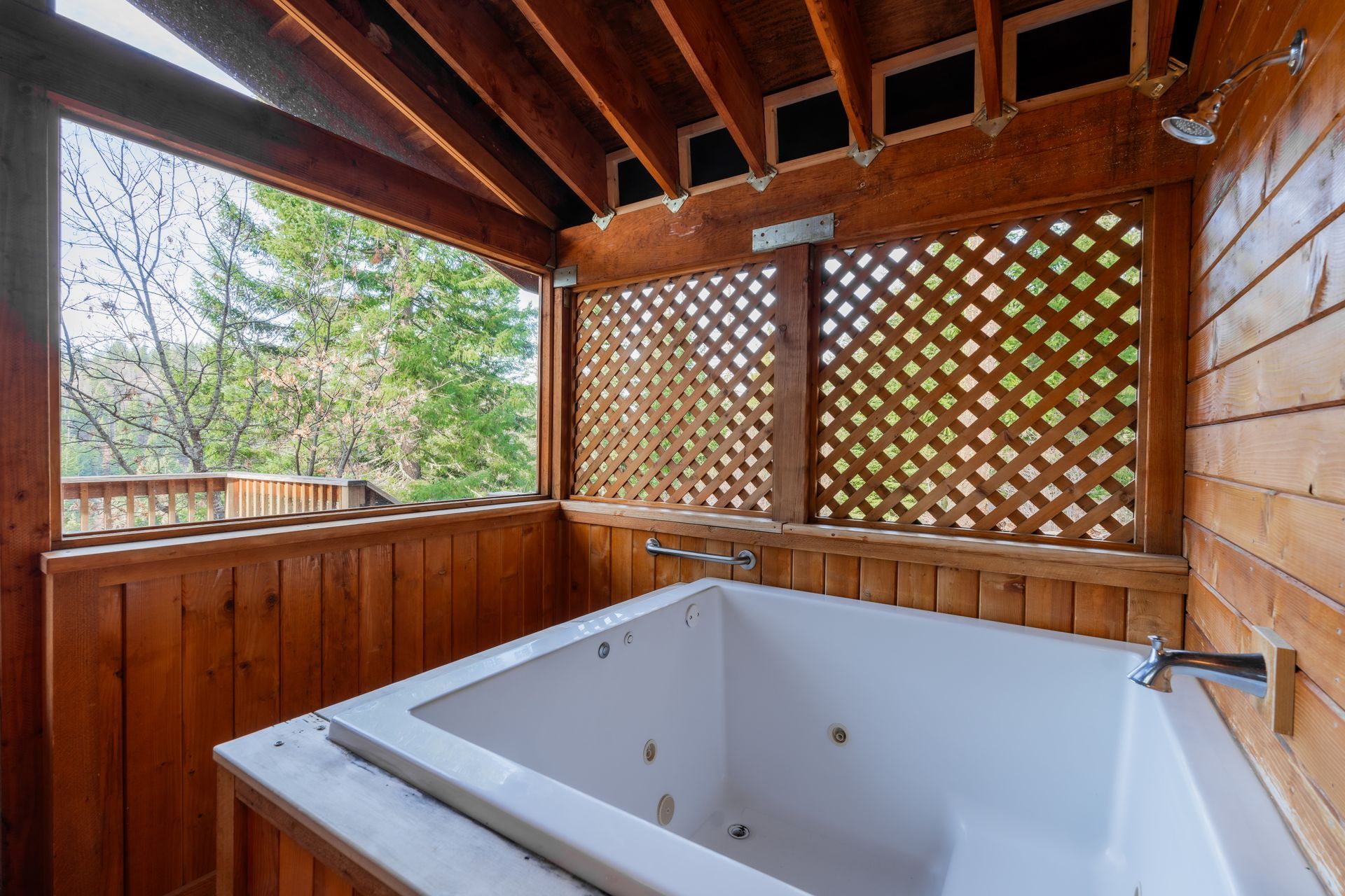 There is a jacuzzi tub on the porch of a cabin.