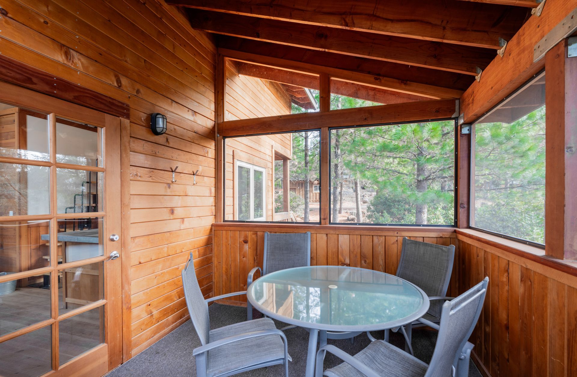 There is a screened in porch with a table and chairs.