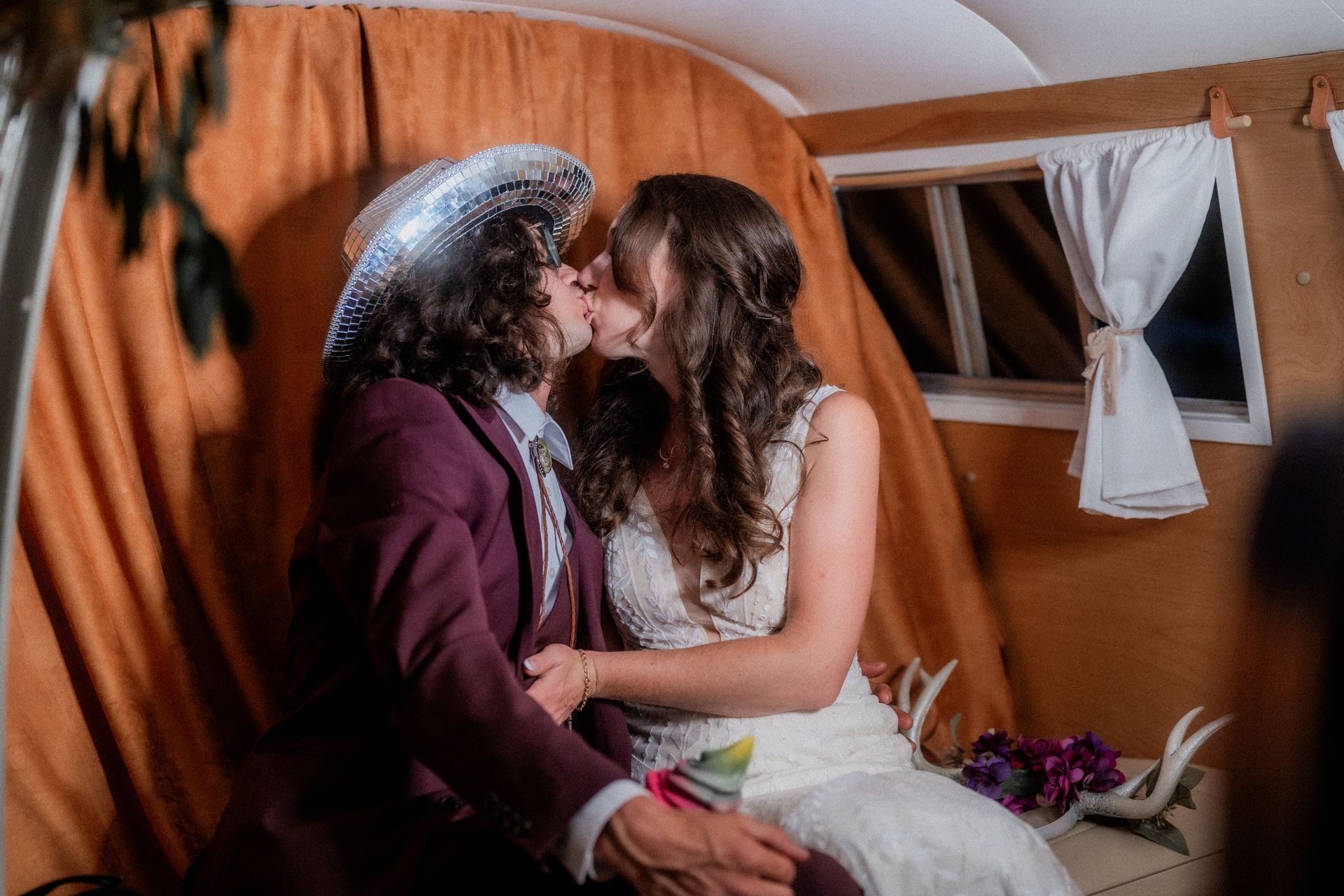 A bride and groom are kissing in a photo booth.