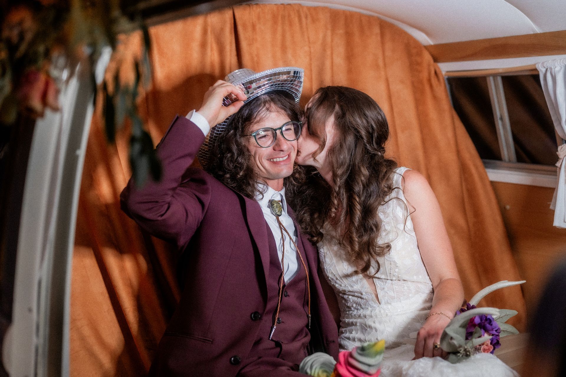 A bride and groom are kissing in a photo booth.