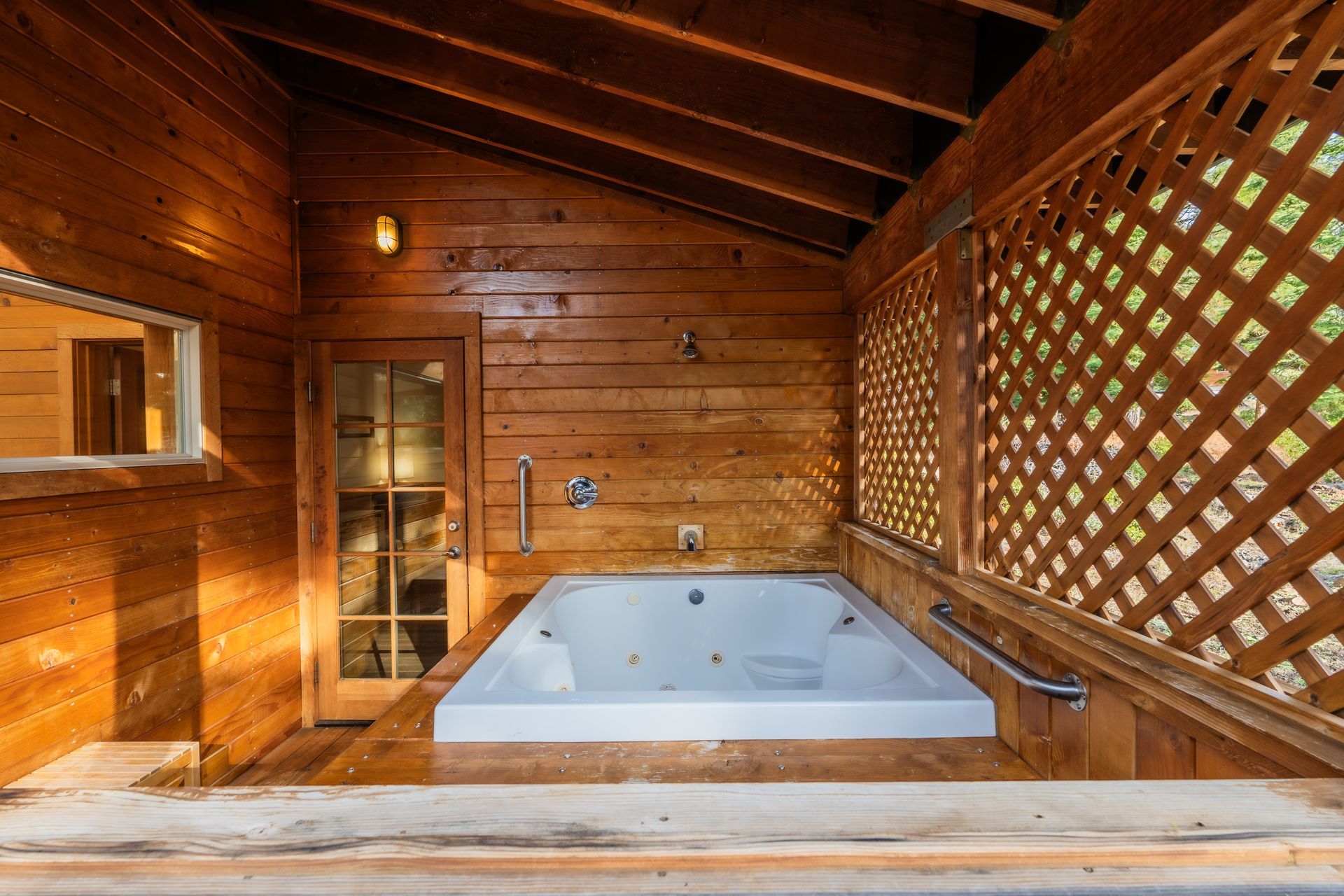 There is a jacuzzi tub in the middle of a wooden room.