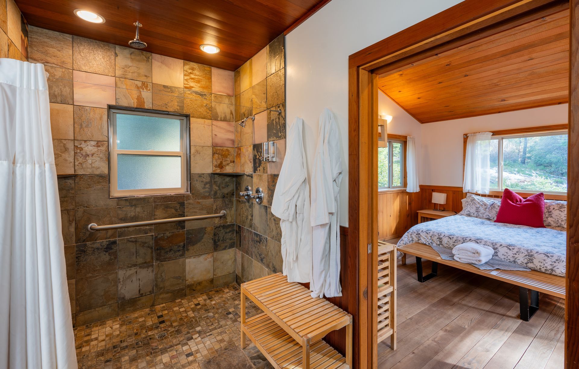 A bathroom with a walk in shower and a bed.