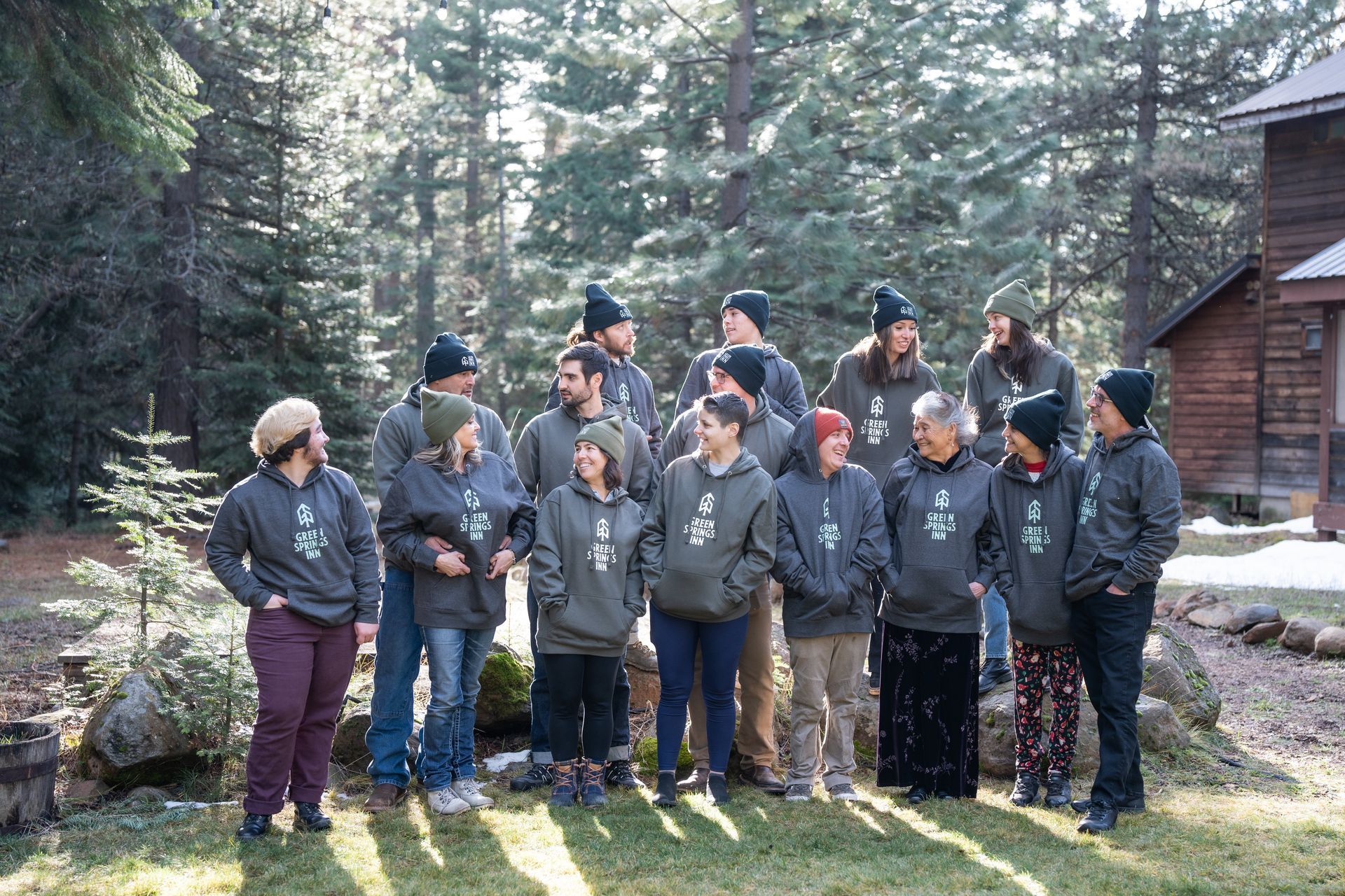 A group of people are standing in front of a cabin in the woods.