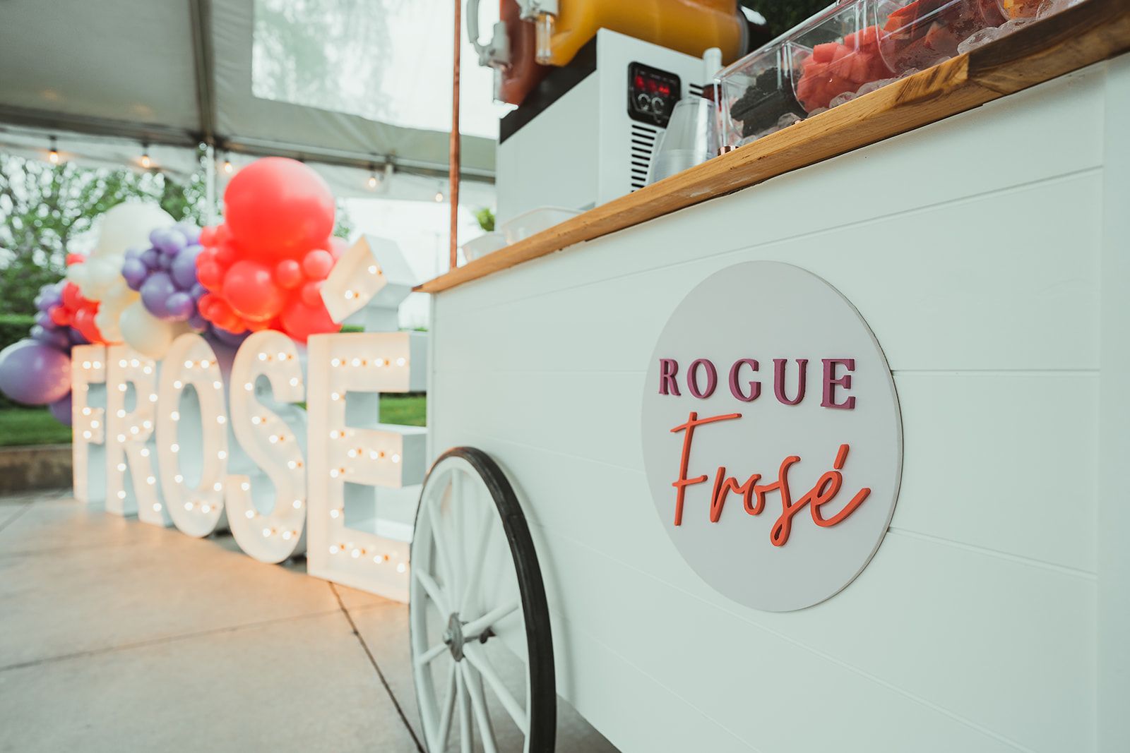 A white cart with a sign that says `` rogue frose '' is sitting under a tent.