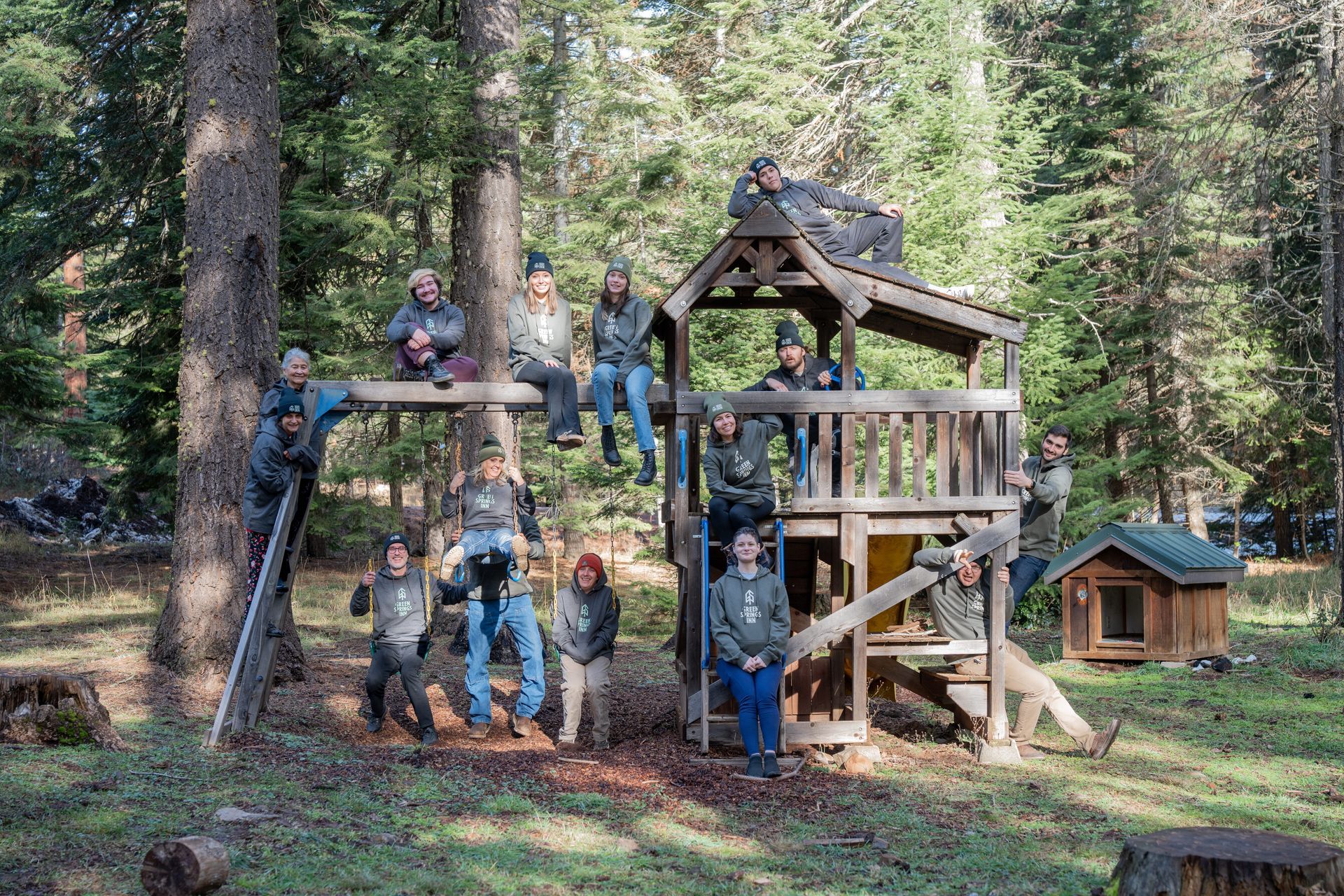 A group of people are posing for a picture on a playground in the woods.