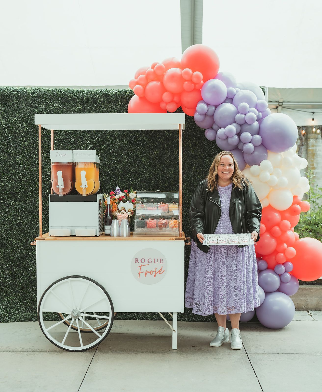A woman is standing in front of a cart decorated with balloons.