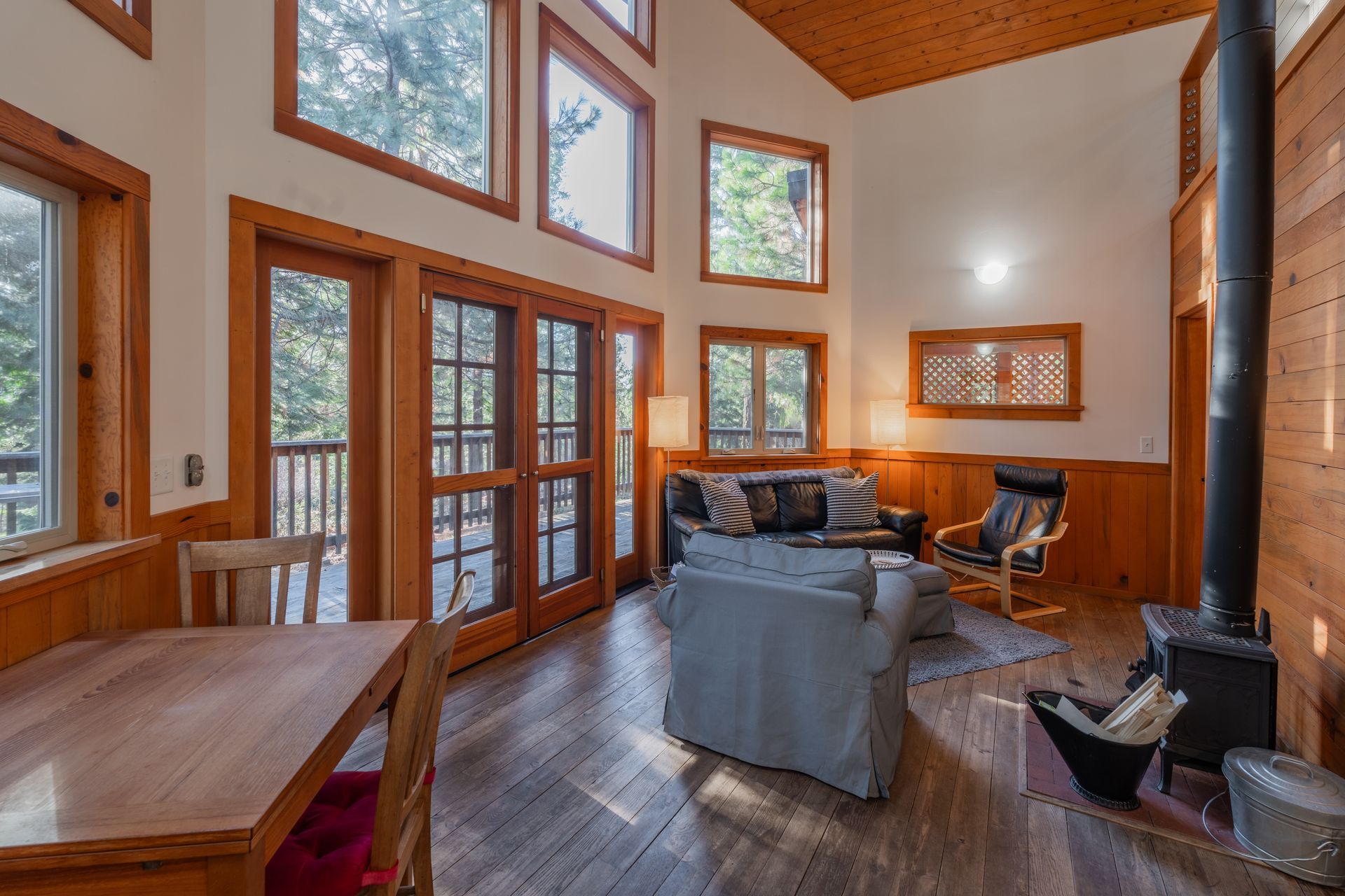 A living room in a cabin with a couch , chair , table and fireplace.