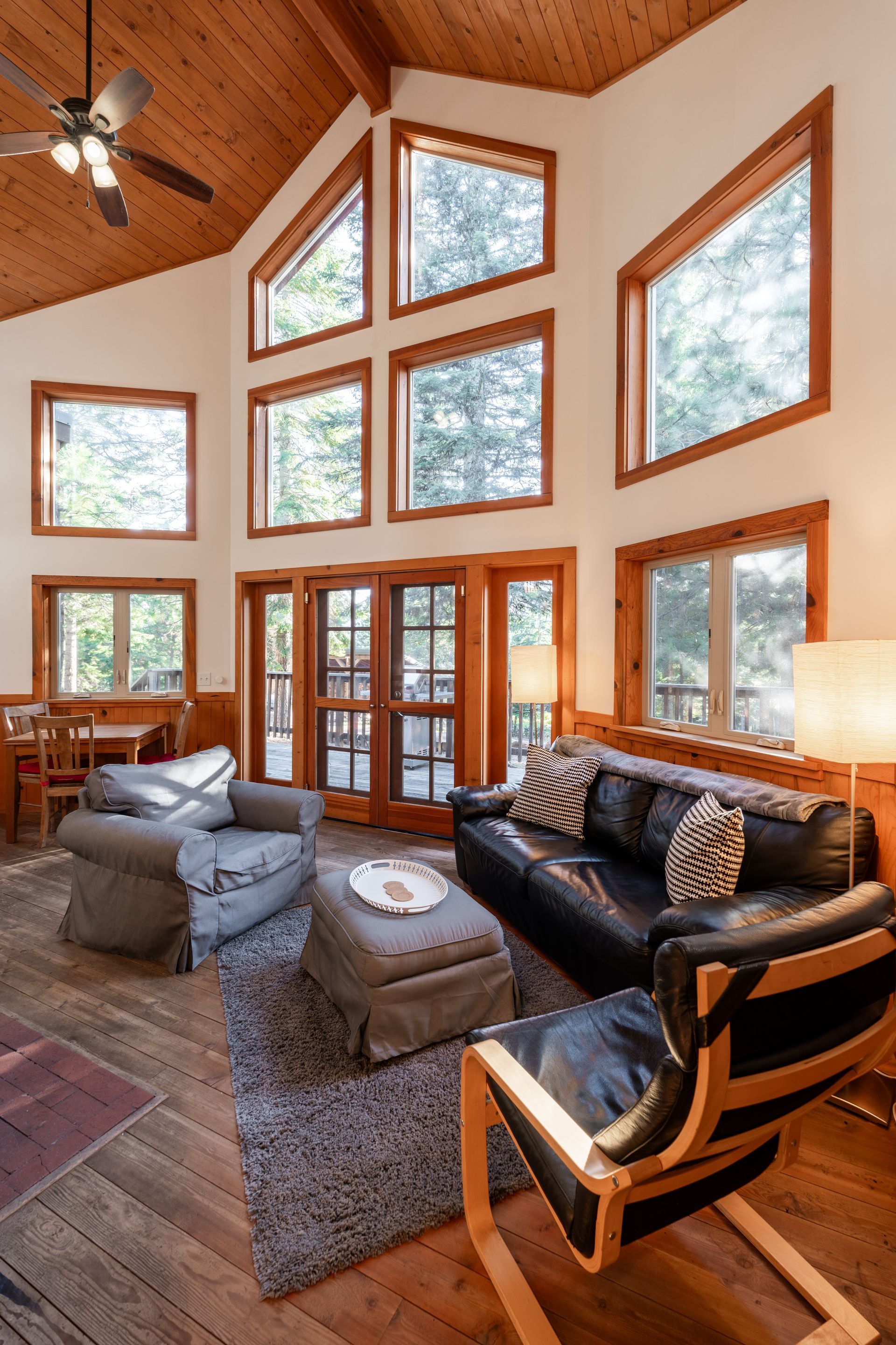 A living room with a couch , chairs , ottoman and ceiling fan.