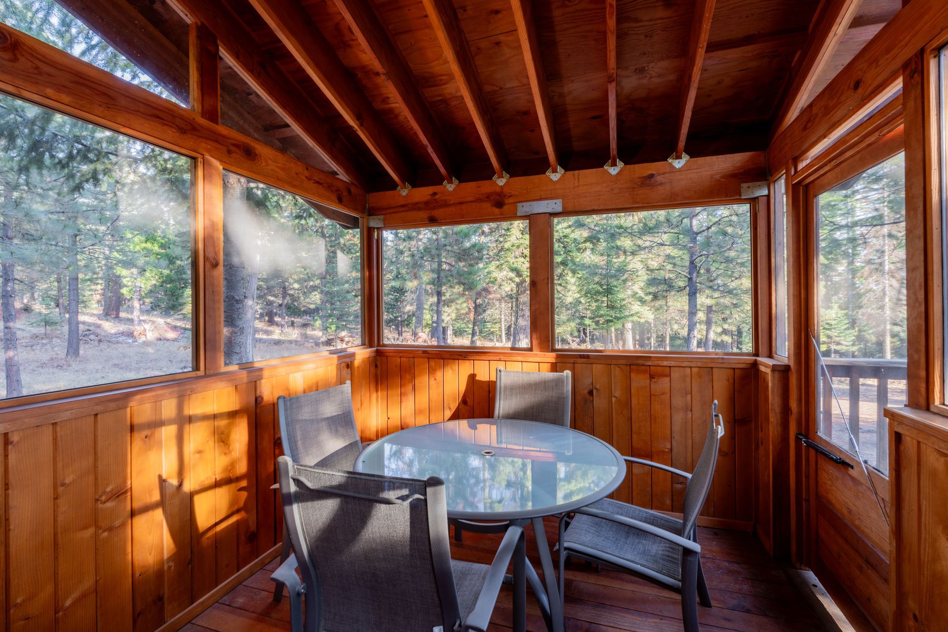 A screened in porch with a table and chairs.