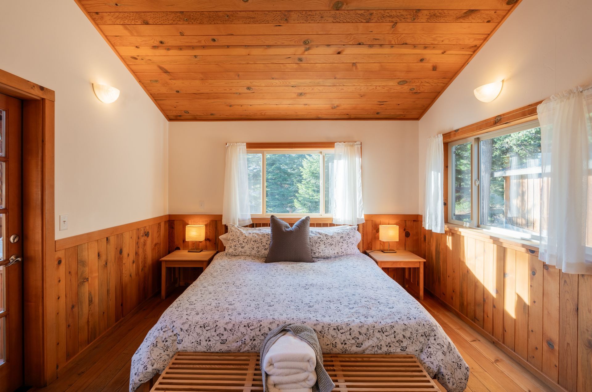 There is a bed in the middle of the room with wood paneling.