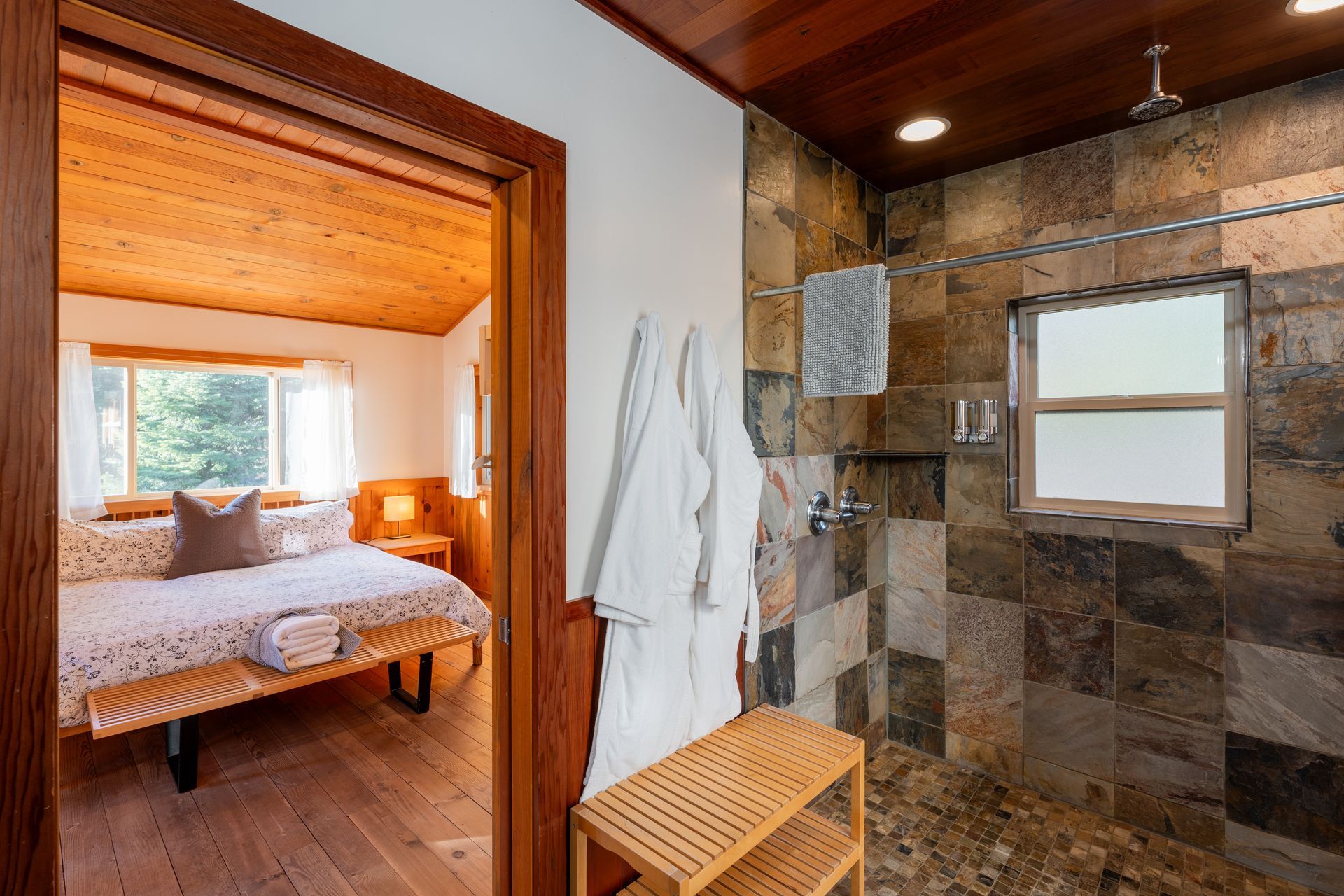 A bathroom with a walk in shower and a bedroom with a bed.