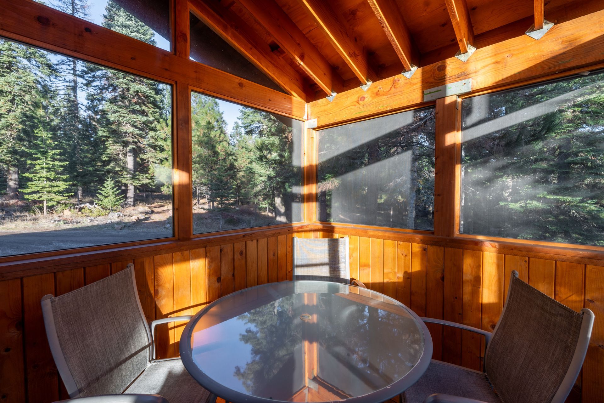 A screened in porch with a table and chairs