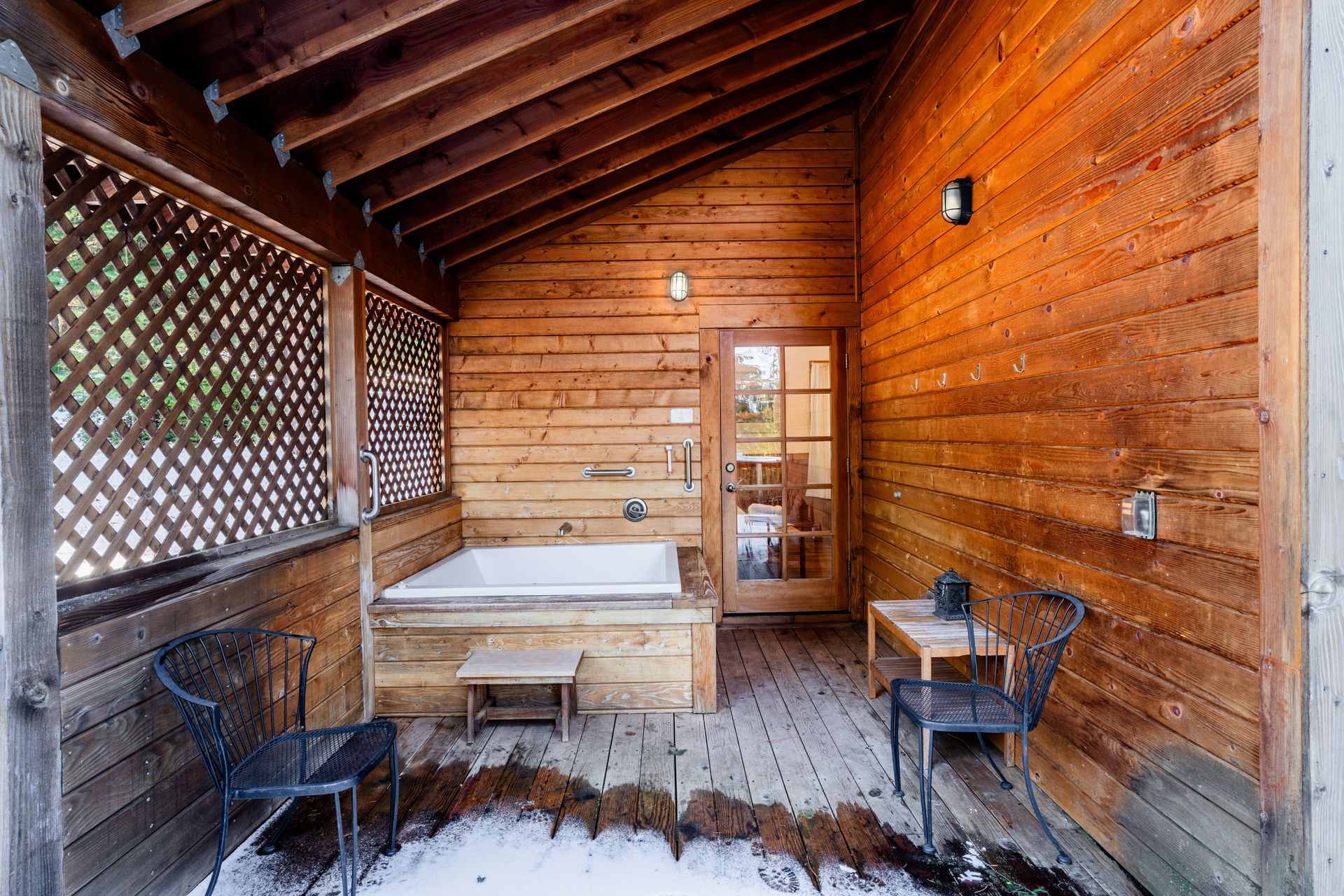 A wooden cabin with a hot tub in the backyard.