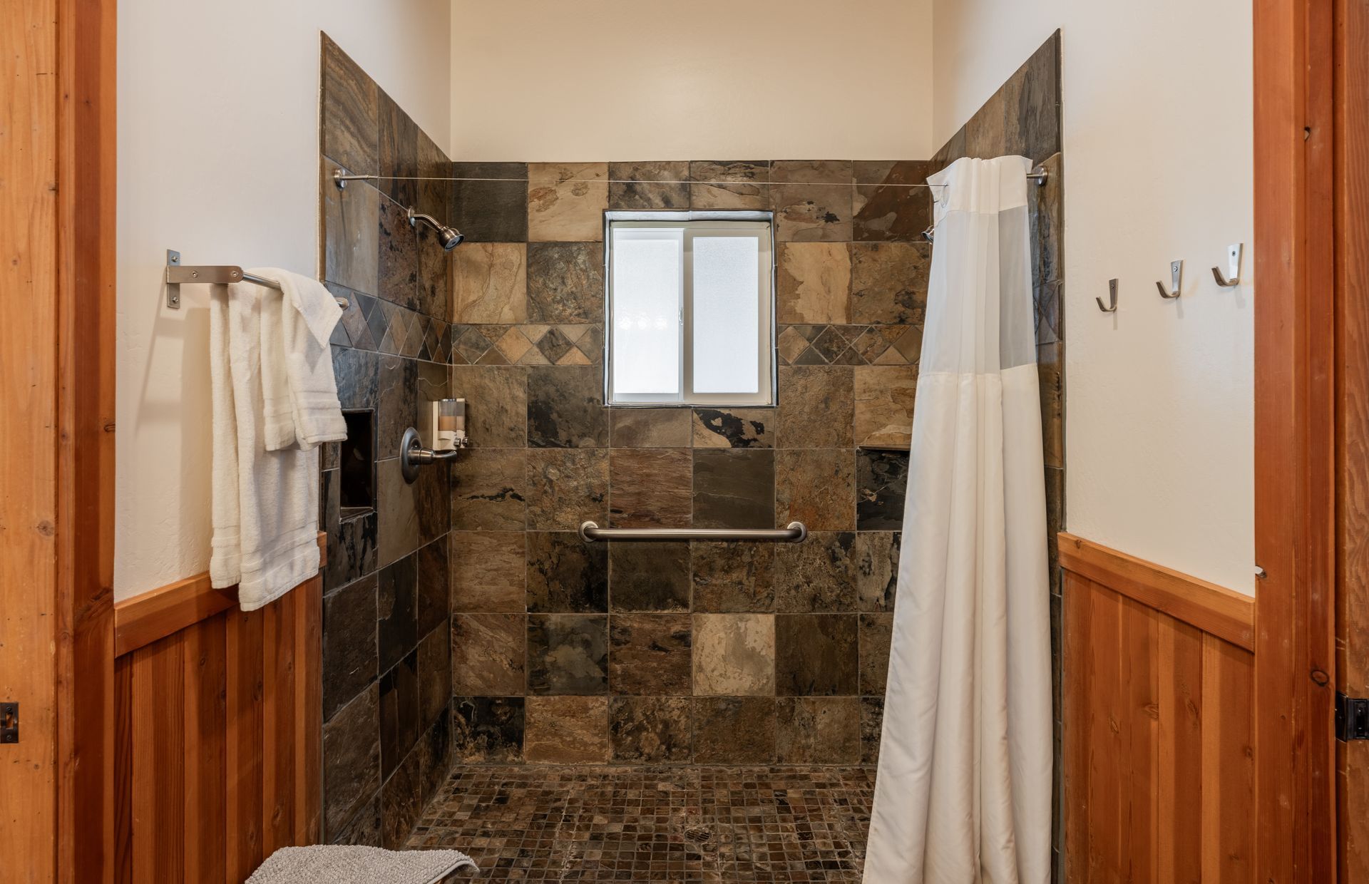 A bathroom with a walk in shower and a window.