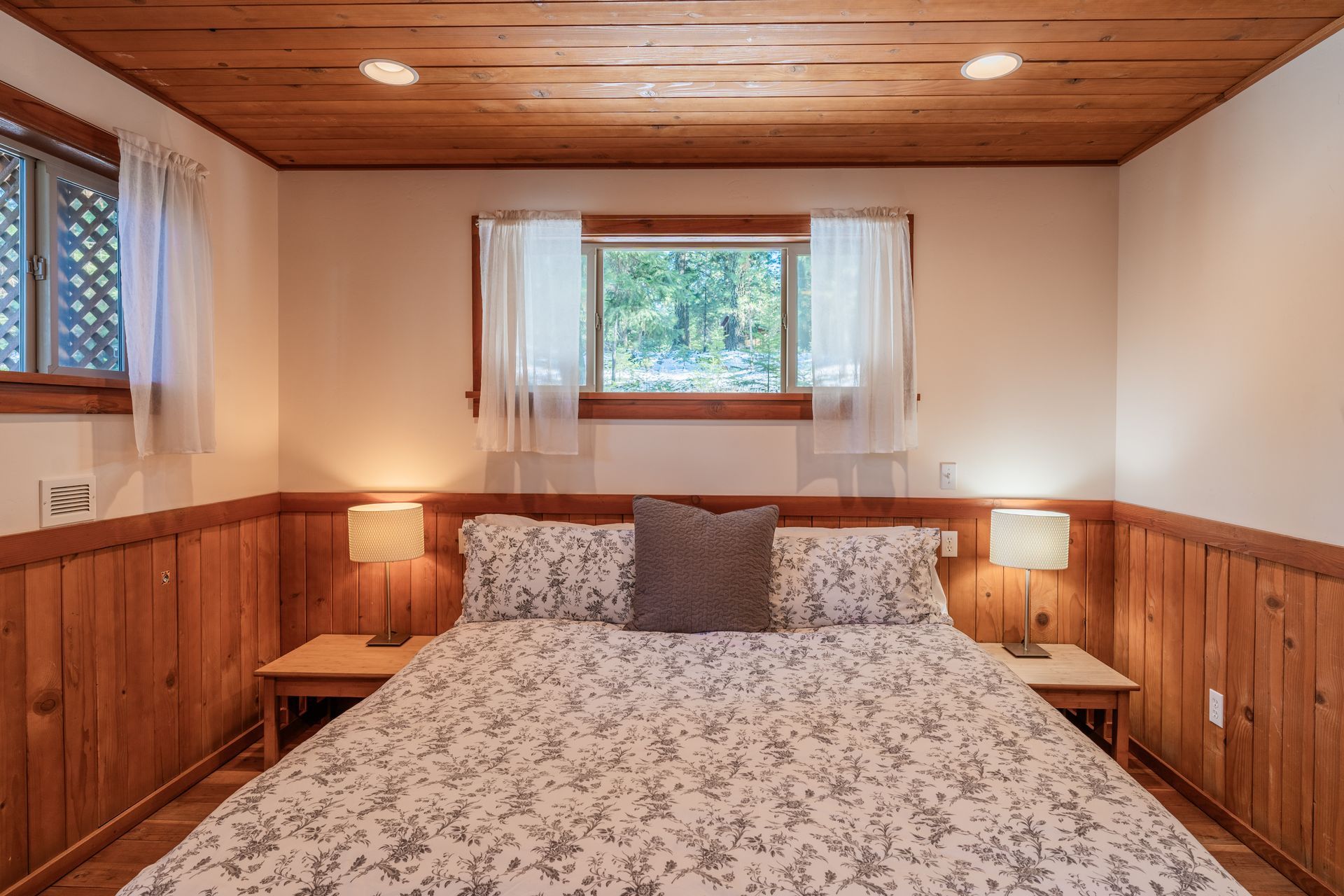 A bedroom with a bed , nightstands , lamps and a window.