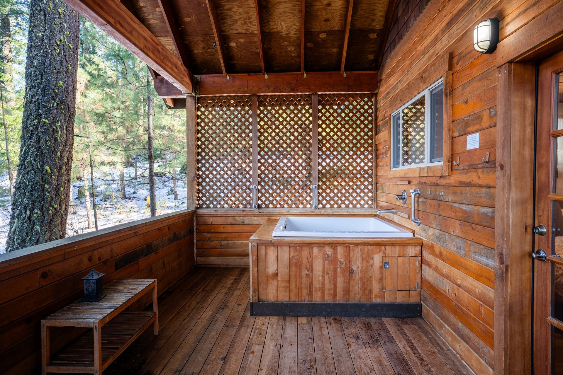 A wooden porch with a jacuzzi tub in the middle of it.