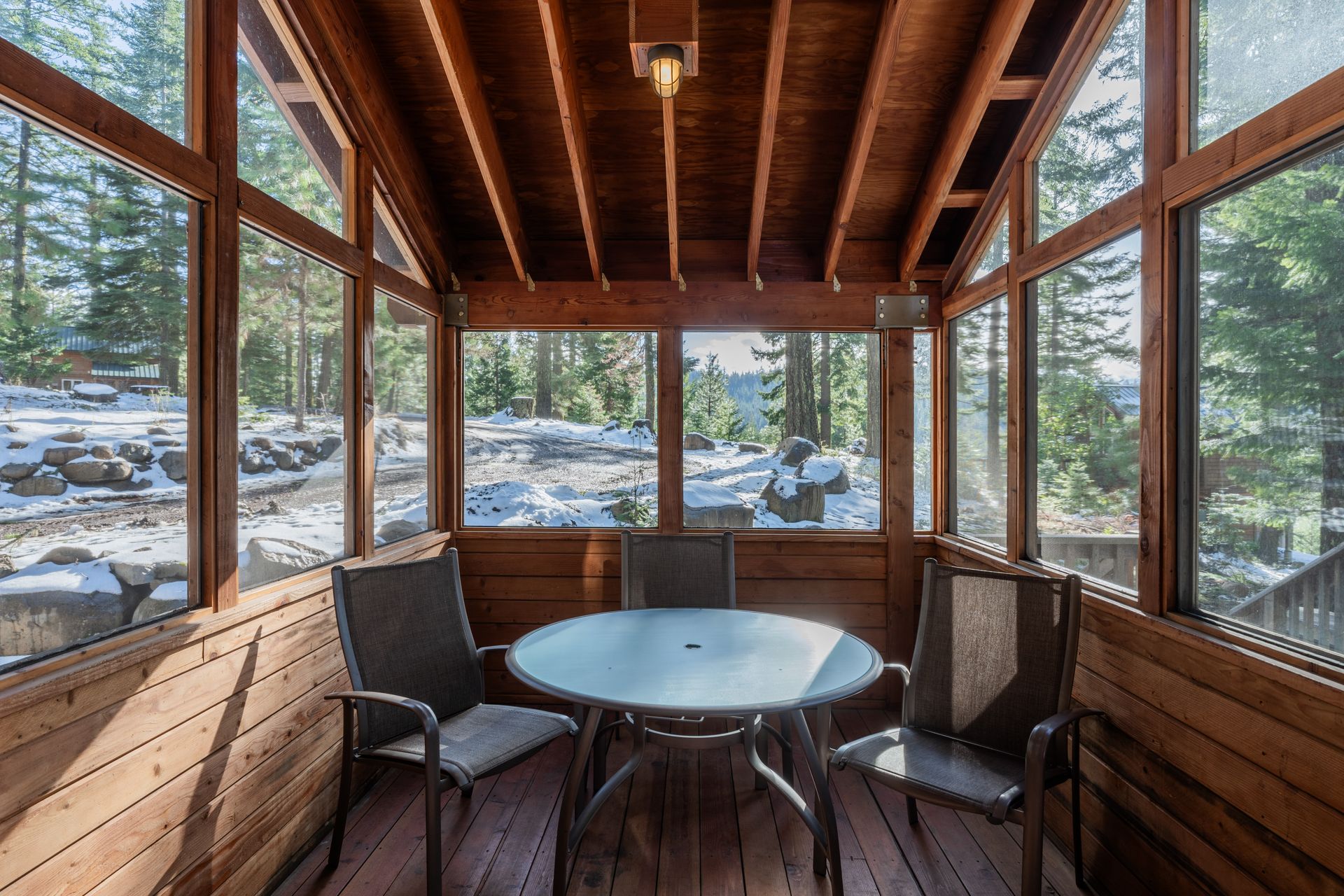 A screened in porch with a table and chairs.