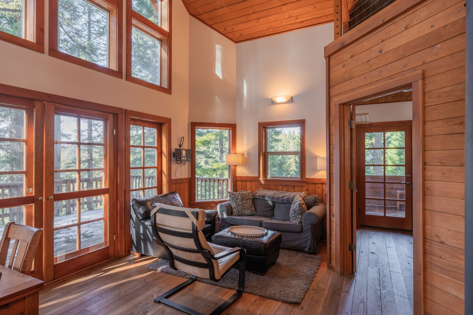 A living room with a couch , chair , coffee table and lots of windows.