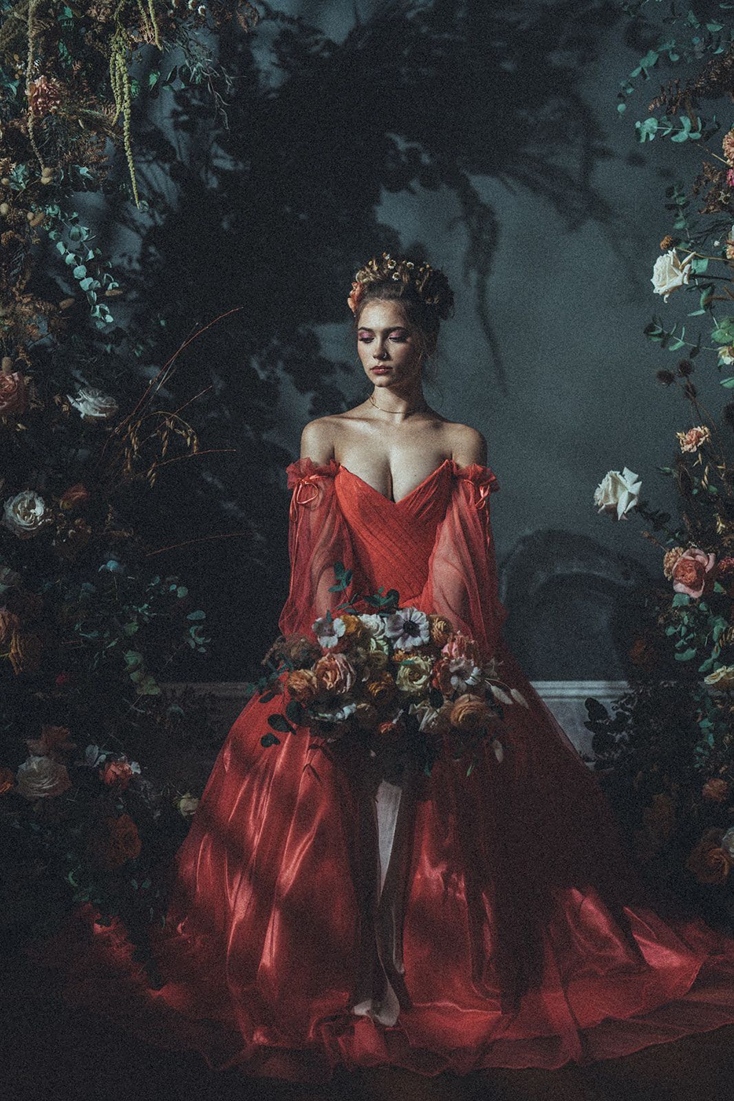 A woman in a red dress is holding a bouquet of flowers.