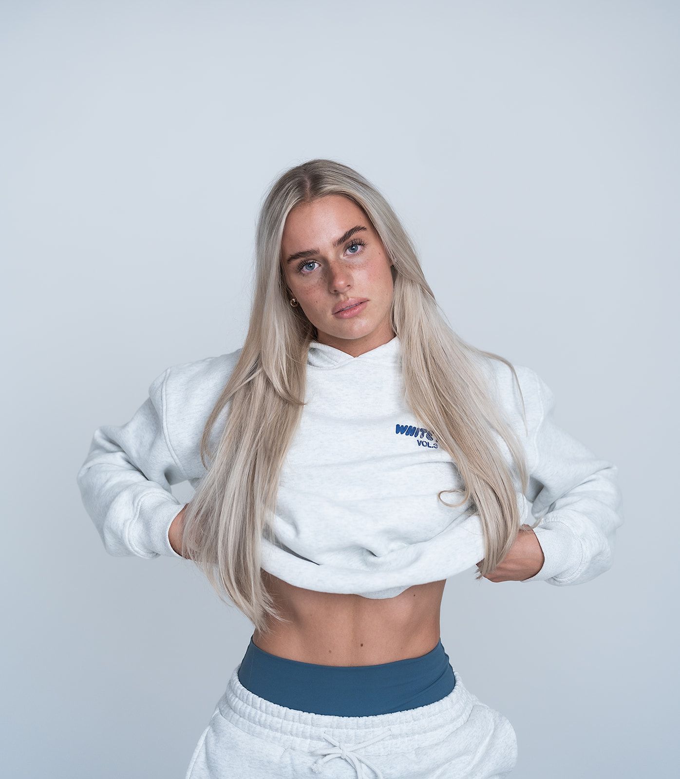 A woman is wearing a white sweatshirt and white sweatpants.