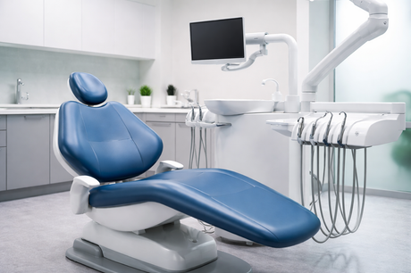 Blue dental chair in a clean, modern dental office with tools and a monitor.